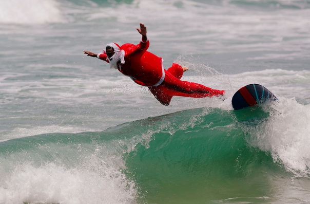 Инструктор по серфингу Карлос Баия занимается серфингом в костюме Санта-Клауса на пляже Маресиас в Сан-Себастьян, Бразилия Последние шесть лет серфер наряжается на Рождество Санта-Клаусом,